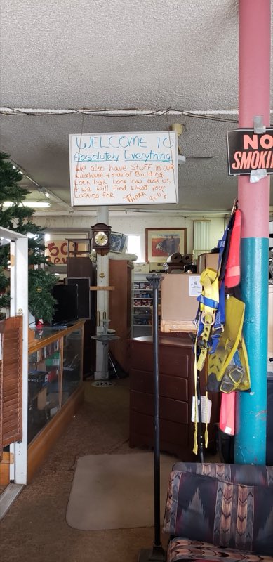 Handwritten welcome sign hanging inside the store above clocks and furniture